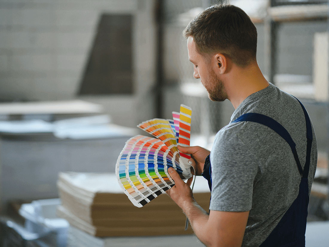 A man holding a color palette in a warehouse.