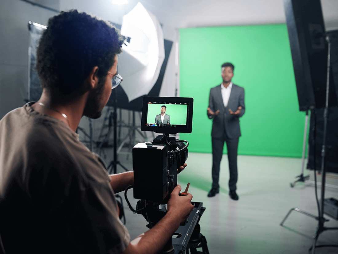 A man is filming a video in a green screen studio.